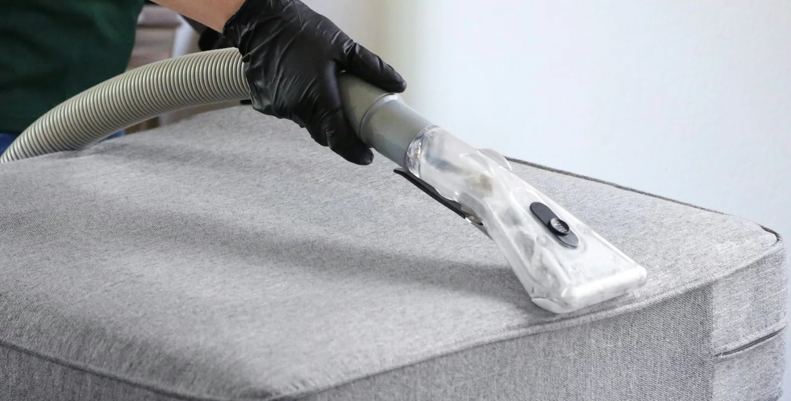 An upholstery tool cleaning a fabric couch cushion